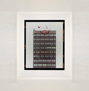 White framed photograph by Richard Heeps. High rise offices with Martini logo on the top facade. 