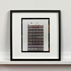 Black framed photograph by Richard Heeps. High rise offices with Martini lgoo on the top facade. 