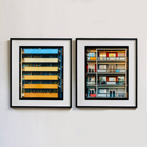 Two black framed photographs by Richard Heeps. Two photographs of apartment buildings, the one on the left with coloured balconies, blue at the top balcony and then fading from light yellow to a sunburnt yellow at the bottom. The photograph on the right is four floors of different coloured walls on four different different floors.