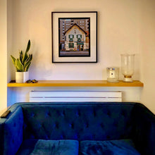 Load image into Gallery viewer, In situ black framed photograph by Richard Heeps. A traditional Italian Tobacconist shop, here in a Swiss Cottage style building set against a vast urban apartment block.
