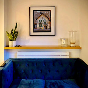 In situ black framed photograph by Richard Heeps. A traditional Italian Tobacconist shop, here in a Swiss Cottage style building set against a vast urban apartment block.