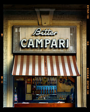 Load image into Gallery viewer, Photograph by Richard Heeps. A shop selling drinks, it has a red and white awning and the shop is called Bitter Campari in white lettering. This photograph has a black rebate.