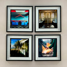 Load image into Gallery viewer, 4 black framed photographs in a square by Richard Heeps. The first photograph captures the inside of a Wimpy Restaurant in Norfolk. There is bright blue seats and red tables. The walls are blue and there is a big red chevron light attached to the wall. The second photograph is the inside of a subway car in NY, the bottom left photograph is a lovely palm tree outside a cream building on the beach. The last photograph on the bottom right is two hands held with a fire roaring behind, and trees behind the fire.