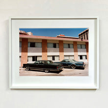 Load image into Gallery viewer, White framed photograph by Richard Heeps. This retro photograph has two classic Lincoln cars parked outside a hotel in Las Vegas. 