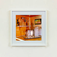 Load image into Gallery viewer, White framed photograph by Richard Heeps. A drinks corner with martini glasses, cocktail shaker and ice bucket. There is a shelf with cocktail making equipment and it is set against retro orange walls.