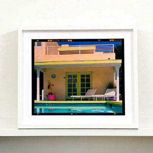 White framed photograph by Richard Heeps. Palm Springs Pool Side II showcases classic mid-century Palm Springs California architecture. Cool blue skies and pool with accents of pink and almost neon yellow. 