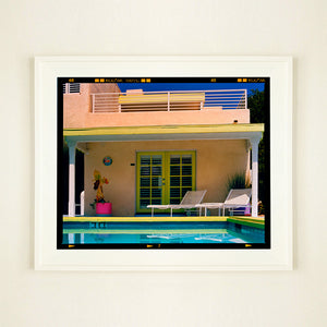 White framed photograph by Richard Heeps. Palm Springs Pool Side II showcases classic mid-century Palm Springs California architecture. Cool blue skies and pool with accents of pink and almost neon yellow. 
