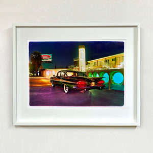 White framed photograph by Richard Heeps. A Chevy Bel Air is central shot and off to the right are the pools and balcony of the Glass Pool Motel, Las Vegas.