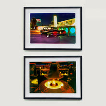 Load image into Gallery viewer, Two black framed photographs by Richard Heeps. Both retro photographs, one  has a Chevy Bel Air sitting in front of the Glass Pool Motel, Las Vegas. The photo at the bottom is an indoor fire pit surrounded by a circular table and a circular golden hood over the top.  The photo is taken in a mirrored bar which echoes the fire pit and hood all around this golden, dark lit bar.
