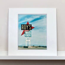 Load image into Gallery viewer, Mounted photograph by Richard Heeps. A roadside sign on Route 66 in America. The word ROY&#39;S appears in a black sign with a big red arrow pointing to the left ground, below this VACANCY and on a green square the words MOTEL and CAFE.