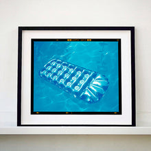 Load image into Gallery viewer, Black framed photograph by Richard Heeps. A transparent blue lilo is sun bathing on a blue pool. 