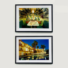 Load image into Gallery viewer, Two black framed photographs by Richard Heeps. The top photograph is inside a trailer, there is a fixed table and chairs with two tea cups and saucers on the table. Behind on the shelf is a tea set and a doll dressed as a bride. The bottom photograph is a hotel and its reflection in the swimming pool taken at night time, lit by the hotel lights.