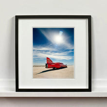 Load image into Gallery viewer, Black framed photograph by Richard Heeps. A red drag car with a 75 written on its fin sits on a salt plain the front facing away towards the right.  A blue cloudy sky is overhead.
