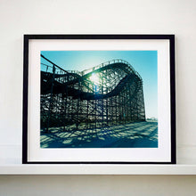 Load image into Gallery viewer, Black framed photograph by Richard Heeps. Great White Roller coaster sits empty on the beach in the setting sun.