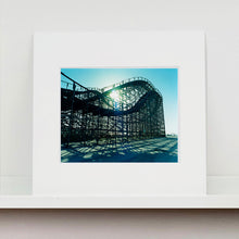 Load image into Gallery viewer, Mounted photograph by Richard Heeps. Great White Roller coaster sits empty on the beach in the setting sun.