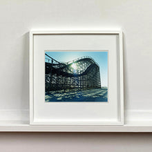 Load image into Gallery viewer, White framed photograph by Richard Heeps. Great White Roller coaster sits empty on the beach in the setting sun.