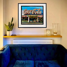 Load image into Gallery viewer, In situ black framed photograph by Richard Heeps. Harry&#39;s Corner was taken on the wildwood boardwalk, featuring neon typography and the iconic Coca-Cola sign against a bright blue sky. 