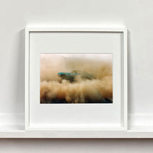 Load image into Gallery viewer, White framed photograph by Richard Heeps. A side view of a light blue Buick car moving and slightly obscured by the dust clouds which it has created.