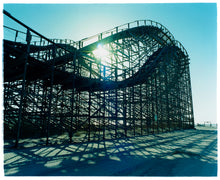Load image into Gallery viewer, Photograph by Richard Heeps. Great White Roller coaster sits empty on the beach in the setting sun.