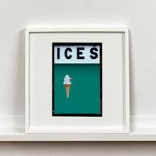 Load image into Gallery viewer, White framed photograph by Richard Heeps.  At the top black letters spell out ICES and below is depicted a 99 icecream cone sitting left of centre against a deep green teal coloured background.  