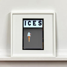 Load image into Gallery viewer, White framed photograph by Richard Heeps.  At the top black letters spell out ICES and below is depicted a 99 icecream cone sitting left of centre against a grey coloured background.  