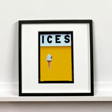 Load image into Gallery viewer, Black framed photograph by Richard Heeps.  At the top black letters spell out ICES and below is depicted a 99 icecream cone sitting left of centre against a mustard yellow coloured background.  