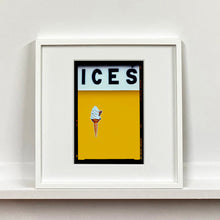 Load image into Gallery viewer, White framed photograph by Richard Heeps.  At the top black letters spell out ICES and below is depicted a 99 icecream cone sitting left of centre against a mustard yellow coloured background.  