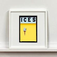 Load image into Gallery viewer, White framed photograph by Richard Heeps.  At the top black letters spell out ICES and below is depicted a 99 icecream cone sitting left of centre against a sherbert yellow coloured background.  