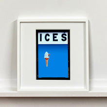 Load image into Gallery viewer, White framed photograph by Richard Heeps.  At the top black letters spell out ICES and below is depicted a 99 icecream cone sitting left of centre against a sky blue coloured background.  