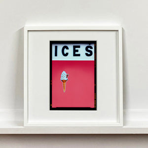 White framed photograph by Richard Heeps.  At the top black letters spell out ICES and below is depicted a 99 icecream cone sitting left of centre against a coral coloured background.  