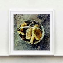 Load image into Gallery viewer, White framed photograph by Richard Heeps. A bucket with sponges, brushes and wooden handled tools sit in a bucket on a cracked cement floor.