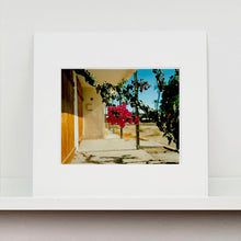 Load image into Gallery viewer, Mounted photograph held by photographer,Richard Heeps. A flowering bougainvillea hangs outside a motel entrance.