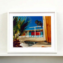 Load image into Gallery viewer, White framed photograph by Richard Heeps. A colourful but derelict vintage motel sits in the blue Californian sun. Palm trees appear behind and to the side. 
