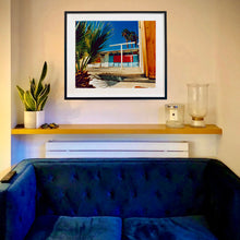 Load image into Gallery viewer, An in situ black framed photograph by Richard Heeps. A colourful but derelict vintage motel sits in the blue Californian sun. Palm trees appear behind and to the side. 