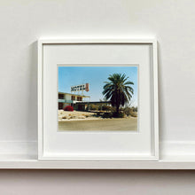Load image into Gallery viewer, White framed photograph by Richard Heeps. A derelict motel office sits on a dusty American road. A large palm tree sits at the front of the office&#39;s walkway.