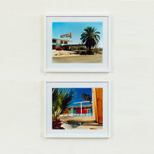 Load image into Gallery viewer, Two white framed photographs by Richard Heeps. The top photograph is of a derelict motel office sitting on a dusty American road. A large palm tree sits at the front of the office&#39;s walkway. The bottom photograph is the outside of a derelict motel, the building has strong colours on it and sits against a beautiful blue sky. There is a palm tree behind the motel and sitting to the left of the scene.