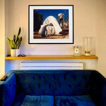 Load image into Gallery viewer, In situ black framed photograph by Richard Heeps. In the foreground of the photograph is a broken off head of a giant fibreglass sculpture of a cowboy (a Muffler Man). In the background set in a deep blue sky is the muffler man&#39;s headless torso.