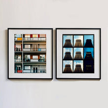 Load image into Gallery viewer, Two black framed photographs by Richard Heeps. The one on the left is the balconies and balcony doors of 4 floors of flats located on the Rue Dezza. The colours of the walls alternate between red and grey but look different as the light catches them. On the right hand side is 9 photos together of a building moving from daylight through to night light.