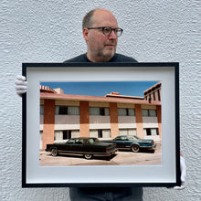 Load image into Gallery viewer, Black framed photograph by Richard Heeps. This retro photograph has two classic Lincoln cars parked outside a hotel in Las Vegas. The photograph is being held by the photographer.