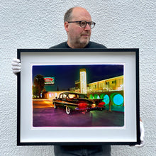 Load image into Gallery viewer, Black framed photograph by Richard Heeps. A Chevy Bel Air is central shot and off to the right are the pools and balcony of the Glass Pool Motel, Las Vegas. The photograph is being held by Richard Heeps.