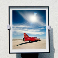 Load image into Gallery viewer, Photograph held by photographer Richard Heeps. A red drag car with a 75 written on its fin sits on a salt plain the front facing away towards the right. A blue cloudy sky is overhead.