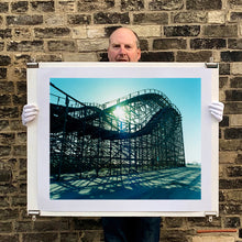 Load image into Gallery viewer, Photograph held by the artist Richard Heeps. Great White Roller coaster sits empty on the beach in the setting sun.