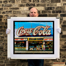 Load image into Gallery viewer, Photograph held by photographer Richard Heeps. Harry&#39;s Corner was taken on the wildwood boardwalk, featuring neon typography and the iconic Coca-Cola sign against a bright blue sky. 
