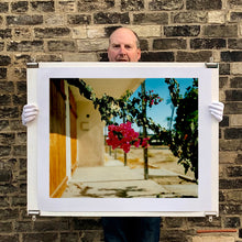 Load image into Gallery viewer, Mounted photograph held by photographer, Richard Heeps. A flowering bougainvillea hangs outside a motel entrance.