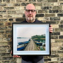 Load image into Gallery viewer, Richard Heeps holding Ormesby Little Broad Norfolk waterscape photograph framed in black.