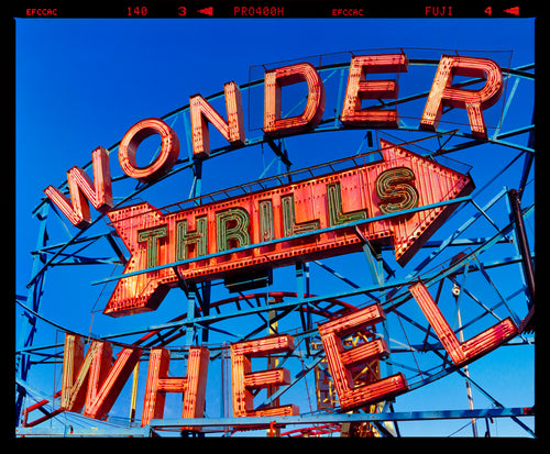 Neon sign for the Wonder Wheel amusement park against a blue sky photograph by Richard Heeps