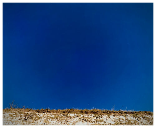 Photograph by Richard Heeps.  A deep blue sky sits over a dry embankment.