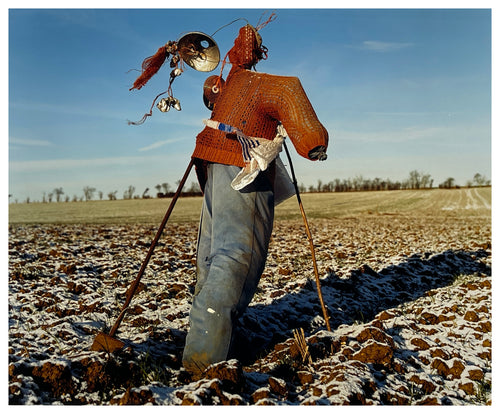 Photograph by Richard Heeps.  A scarecrow in a snowy fen field, dressed in a red jumper and blue jeans.