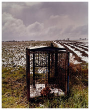 Load image into Gallery viewer, Photograph by Richard Heeps.  A fox trap sits on a field in the snowy fenland of Cambridgeshire.