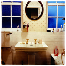 Load image into Gallery viewer, Photograph by Richard Heeps.  A basin, wth gold taps and an oval mirror over the top. There are frosted windows either side of the mirror.  
